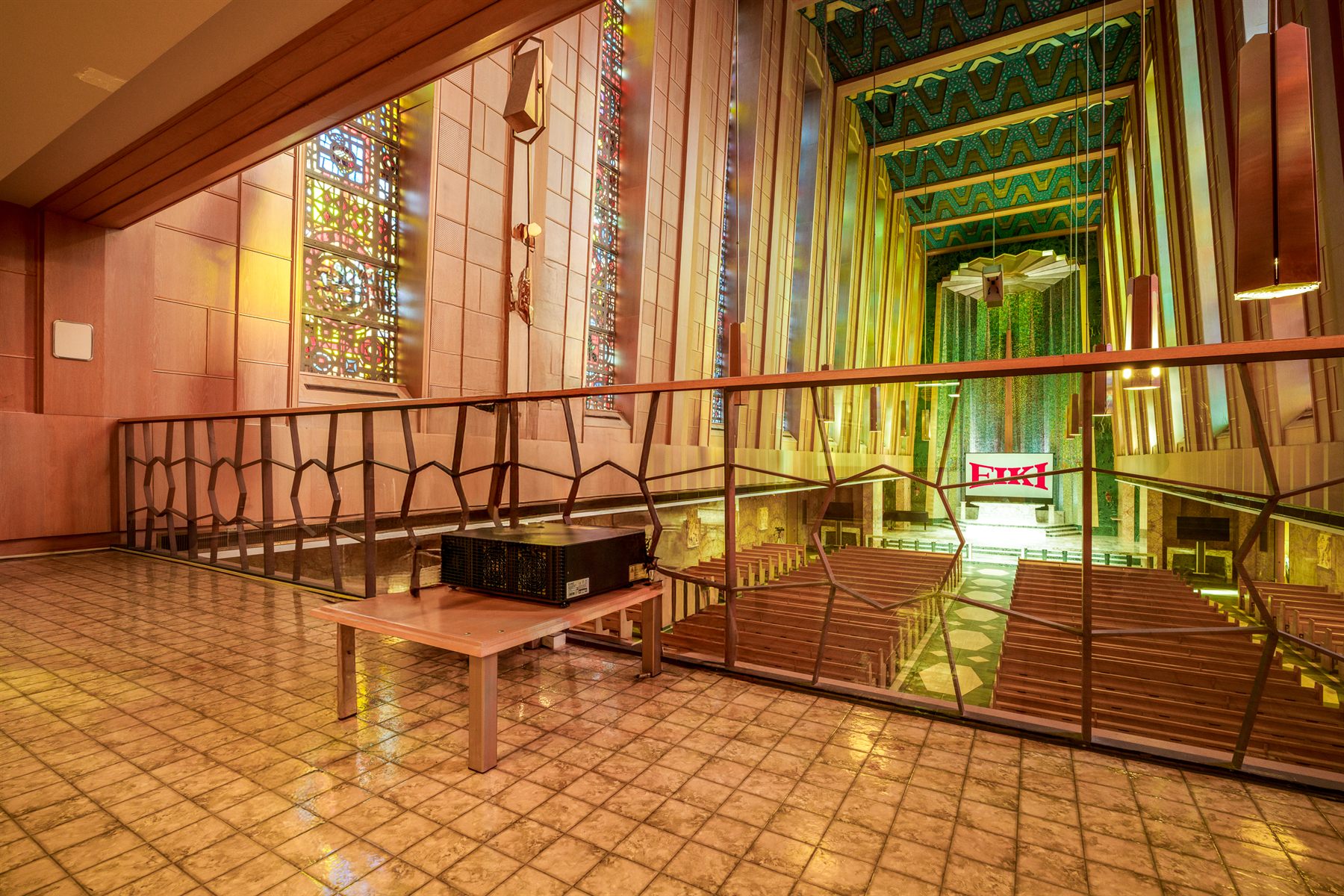 Projector on a balcony platform throwing across the cathedral nave to the altar screen